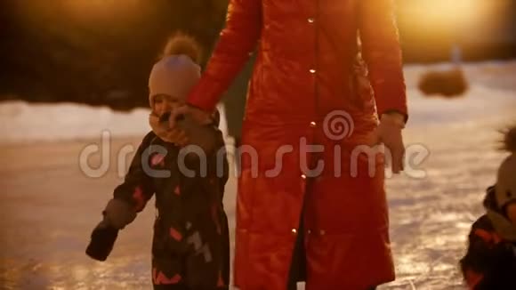 一家年轻的母亲和两个孩子晚上在公共冰场上滑冰视频的预览图