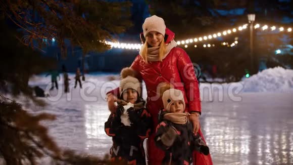 一家年轻的母亲和两个孩子站在装饰好的冰场上用手挥舞着视频的预览图