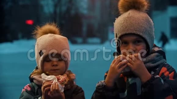 一个小女孩和男孩在户外吃甜甜圈视频的预览图