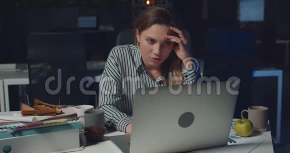 前面看到疲惫过度的女人坐着在办公室里很晚才用笔记本电脑美丽的女孩感到疲惫视频的预览图