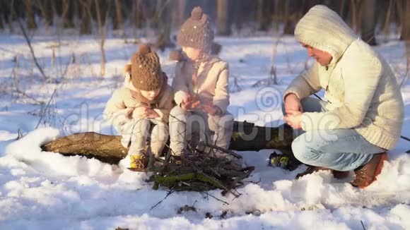 爸爸女儿在冬天的森林里坐着篝火视频的预览图