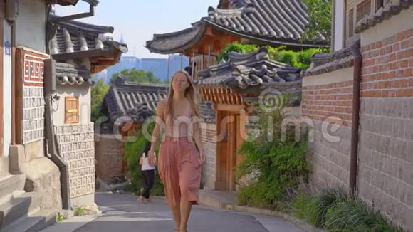 年轻女子参观了韩国首尔市中心的一个繁忙的旅游历史街道BukchonHanok村旅费视频的预览图