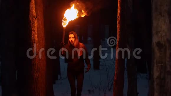 年轻漂亮的女人晚上在树林里手里拿着火炬视频的预览图