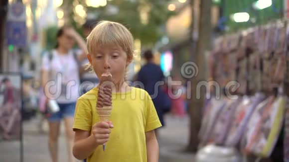 小男孩参观传统的韩国街头市场男孩正在吃一个33厘米长的冰淇淋前往韩国视频的预览图
