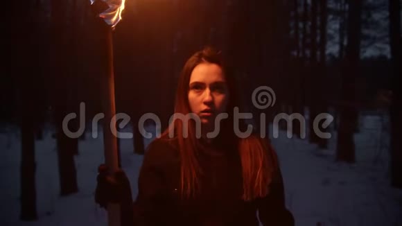 年轻的失落和害怕的女人带着火炬在森林里散步视频的预览图