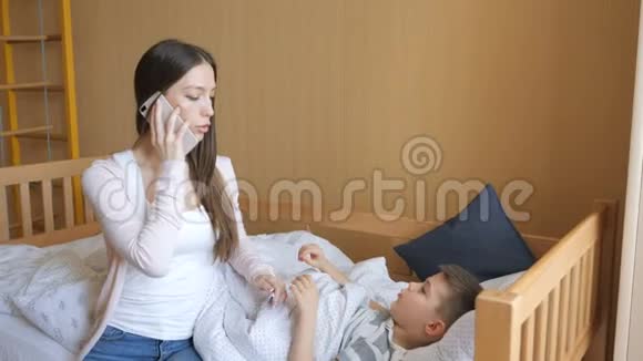 母亲测量生病孩子的体温并给医生打电话视频的预览图
