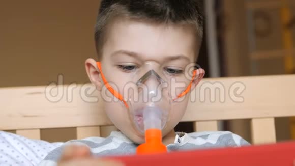 小男孩使用雾化器和玩药片进行治疗性吸入视频的预览图