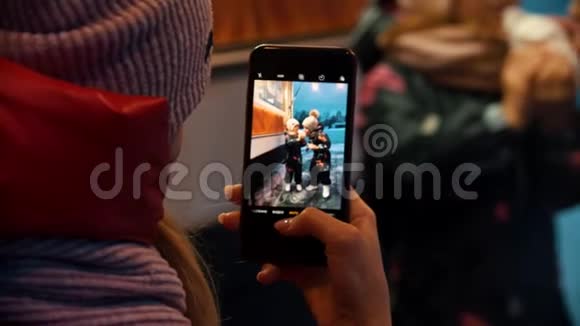 一位年轻的女士为她的孩子们拍照在冬天在户外喝热饮料和吃甜甜圈视频的预览图