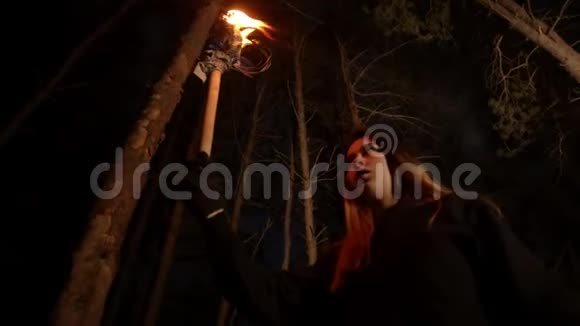 一位年轻的迷路女子手持手工火炬在漆黑的冬林中行走视频的预览图