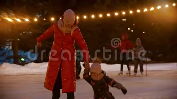 一个年轻的女人和她的女儿在溜冰场滑冰一个女孩摔倒了视频的预览图