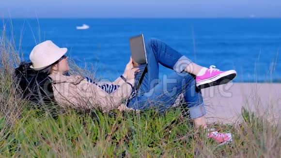 自由职业者女人躺在沙滩上在笔记本上输入文字视频的预览图
