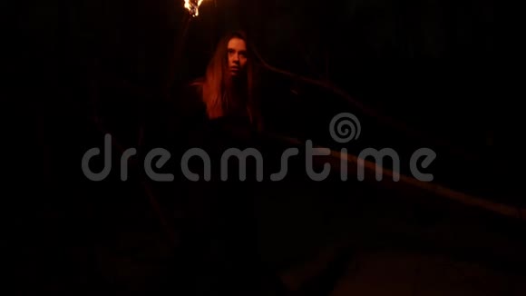 一位年轻的女旅行者晚上在可怕的冬林里用手工火炬行走视频的预览图