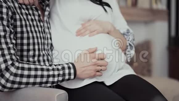 戴着金戒指的男人手在孕妇腹部移动视频的预览图