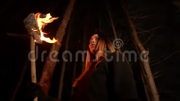 一位年轻的迷路女子站在漆黑的冬林里手里拿着一火炬视频的预览图