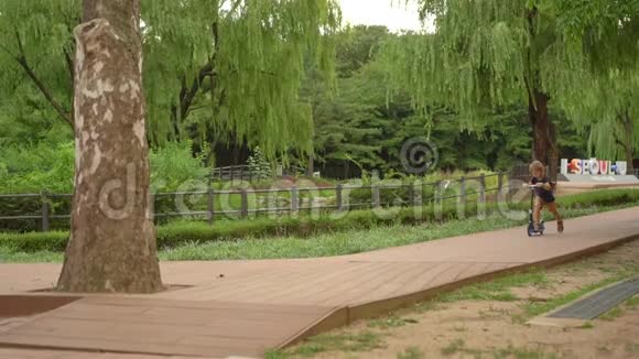 小男孩在公园里骑踢踏车慢镜头视频的预览图