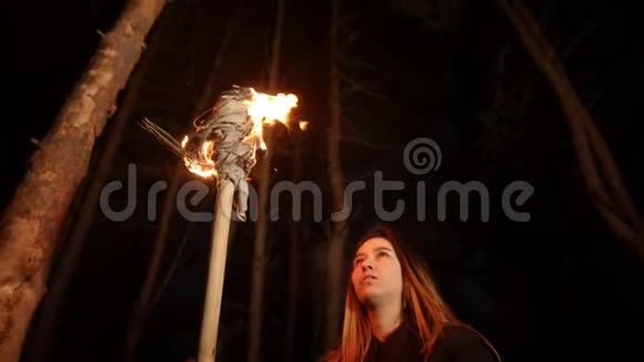 年轻的迷路女子留着长发晚上站在冬天的森林里手里拿着手工火炬视频的预览图