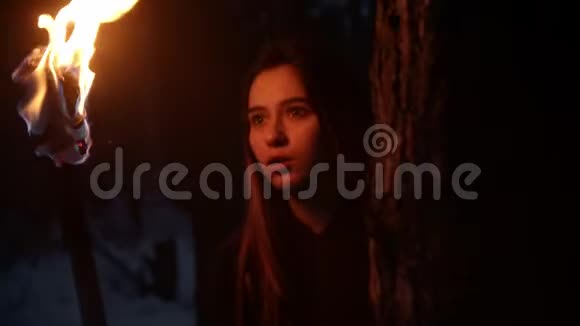 年轻的吓坏了的女人拿着火炬从两边的树上望出去视频的预览图