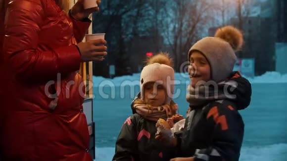 一个年轻的女人和她的孩子一起喝热饮料和吃甜甜圈视频的预览图
