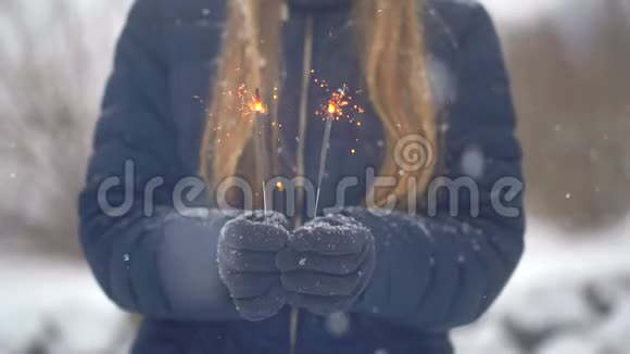 女人在白雪皑皑的背景下手里拿着火花或孟加拉灯视频的预览图