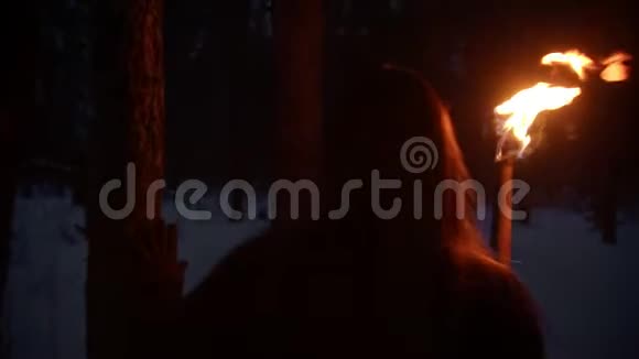 一位年轻的迷路女子拿着火把在森林里散步四处张望视频的预览图