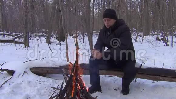 在冬天的森林里一个孤独的人用火温暖他的手视频的预览图