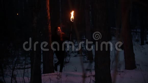 带着火炬在森林中漫步的年轻女子视频的预览图