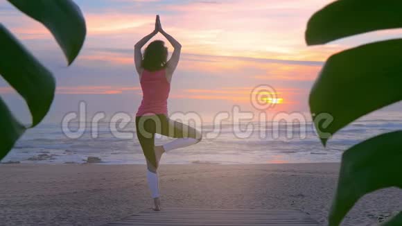 在夏日日落的木步道上做瑜伽的女人视频的预览图