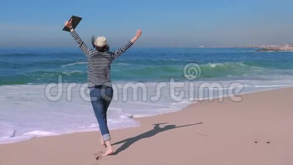 有笔记本电脑的漂亮女人在海滩上得到好消息快乐的旅行女郎视频的预览图
