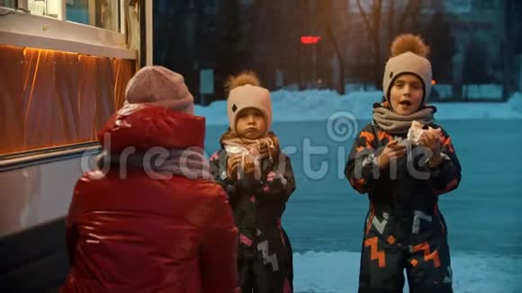 一个年轻的女人带着她的孩子在小商店附近喝热饮料和吃甜甜圈视频的预览图