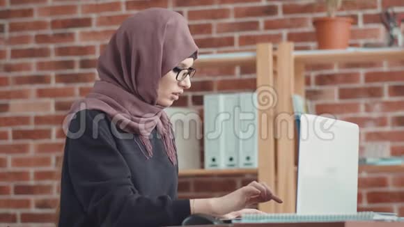 一名穆斯林妇女接听电话并记录信息一个戴着头巾的年轻女孩当经理回答视频的预览图