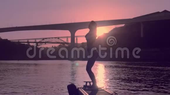 夕阳西下河岸上的年轻舞女视频的预览图