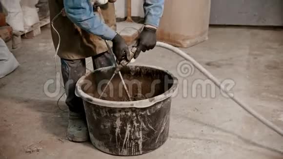 混凝土工业青年工人在装满水泥的桶里加水视频的预览图