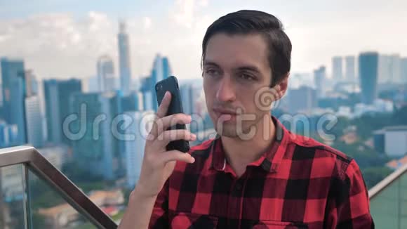 在城市里有智能手机的年轻人打电话摩天大楼背景视频的预览图