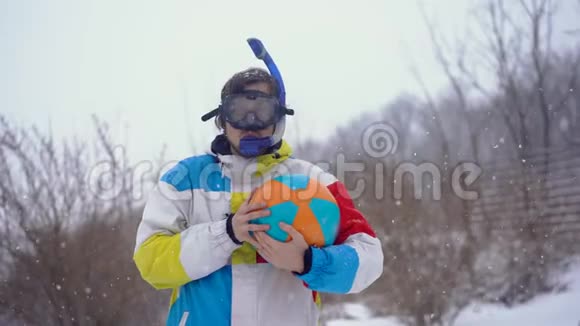 穿着带充气球的潜水面具的滑稽男子站在降雪下失去了时间视频的预览图