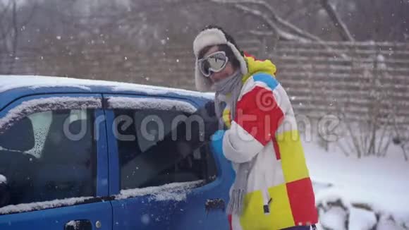 一个年轻人试图把他的滑雪板装在一辆小汽车里但他不到汽车空间不足的概念视频的预览图