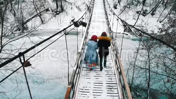 在冬天的森林里两个年轻的女朋友从桥上的热水瓶里喝热饮料视频的预览图
