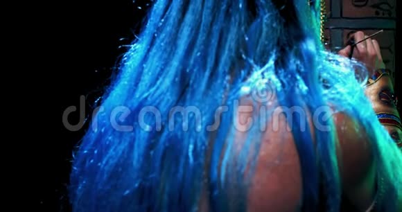 蓝色头发的树站在黑暗的房间里画一根柱子4K视频的预览图