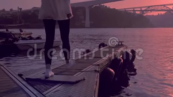 日落时分码头上看到波尔图桥的年轻女子视频的预览图