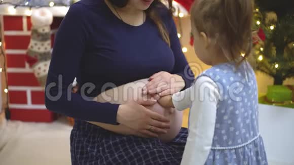 两个孩子摸索着倾听亲吻怀孕母亲的肚子视频的预览图