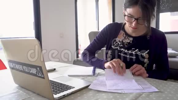 在家里的笔记本电脑前做笔记的女人视频的预览图