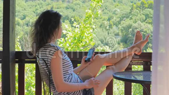 在阳台上听音乐或打电话的年轻女子视频的预览图