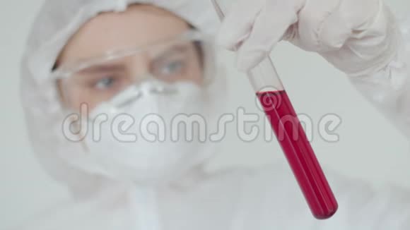 一位戴着化学防护面罩和眼镜的女孩实验室助理用红色溶液看着试管护士带着视频的预览图