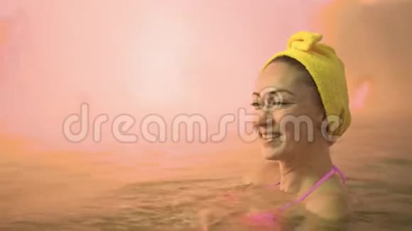在传统的室外水疗中心用柔软的粉红色魔法在热盐水矿物浴中游泳把白种人的女人关起来视频的预览图