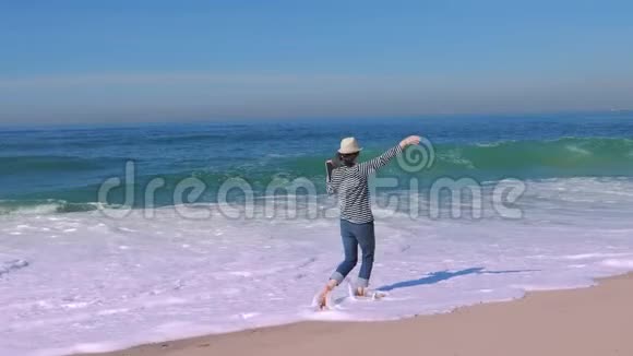 快乐的女人带着笔记本电脑在海滩上奔跑和跳跃视频的预览图