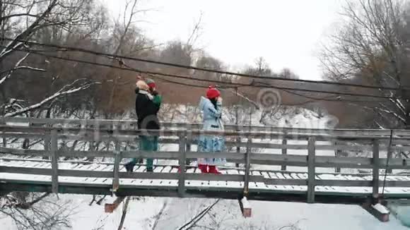 两个年轻的女人从热水瓶里喝热饮料走在桥上视频的预览图