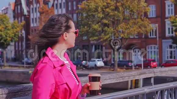 太阳镜迷人的女人喝咖啡欣赏城市景色视频的预览图
