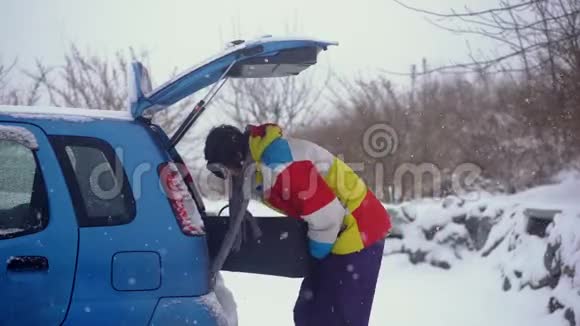 一个年轻人试图把他的滑雪板装在一辆小汽车里但他不到汽车空间不足的概念视频的预览图