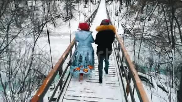 两个年轻的女人从热水瓶里喝热饮料走在雪桥上视频的预览图