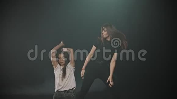 两个迷人的女人在黑暗的工作室里随意跳舞视频的预览图