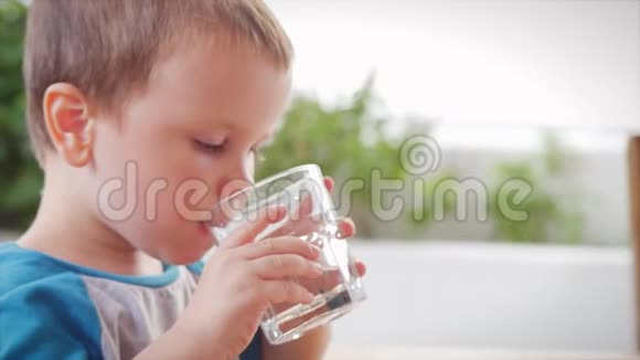 可爱的小男孩在咖啡馆里喝一杯水慢动作小男孩喝水特写镜头孩子是视频的预览图